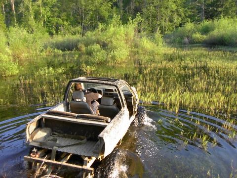 1988 Ford Bronco - A modified off-road vehicle navigates through a wet, grassy terrain.