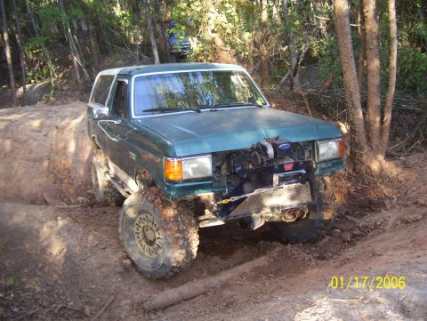 1978 Ford Bronco - This Ford Bronco is navigating a challenging off-road course with steep inclines and dense trees.