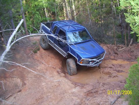 1978 Ford Bronco - Custom blue truck navigates a muddy trail in a wooded area.
