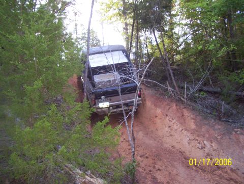 1978 Ford Bronco - 1978 Ford Bronco navigates a challenging off-road trail, climbing a steep dirt embankment.
