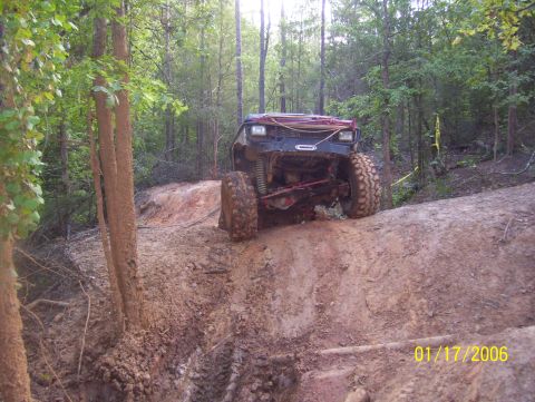 1978 Ford Bronco - This off-road vehicle navigates a challenging muddy incline in a wooded area.
