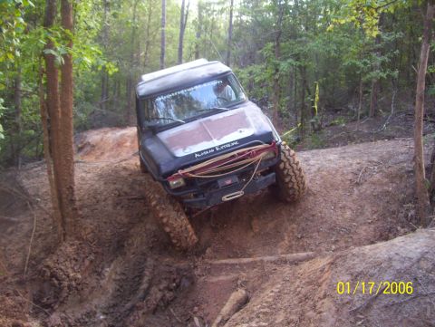 1978 Ford Bronco - Vehicle attempts difficult climb on a wooded, muddy off-road trail.