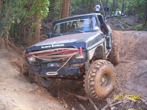 1978 Ford Bronco - A heavily modified, lifted Ford Bronco is shown navigating a muddy off-road trail. The vehicle has large, aggressive tires and visible afte…