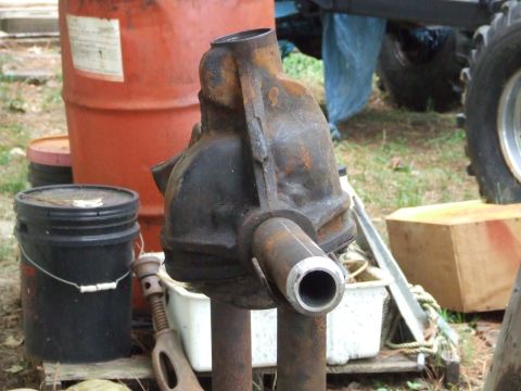 1967 Ford Bronco - A rusty differential housing is shown in a cluttered outdoor setting with various containers and scrap metal.