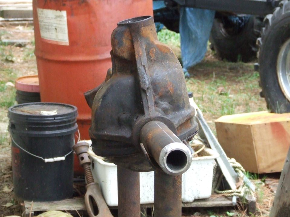 Rusty differential housing with cut pipes, next to orange barrel and black bucket