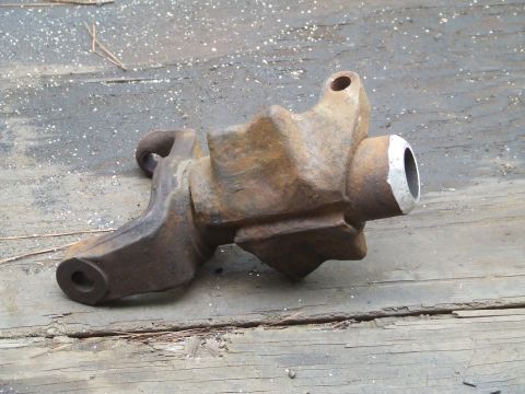1967 Ford Bronco - A close-up view of a heavily rusted metal automotive component resting on weathered wooden planks.