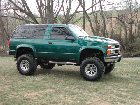1948 Jeep Wrangler - Lifted 1995 Chevrolet Tahoe with off-road tires and a "FOR SALE" sticker on the window.