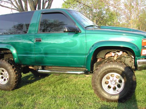 1948 Jeep Wrangler - This lifted green SUV features custom flame graphics along its side and sits on large off-road tires.