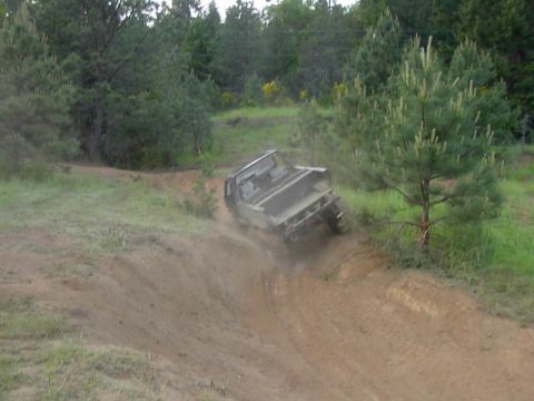 1988 Ford Bronco - A pickup truck navigates a challenging off-road terrain, sending dirt flying.