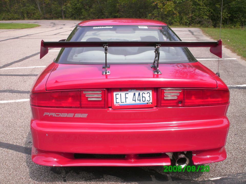 Red 1994 Ford Probe SE with a large rear spoiler and custom exhaust