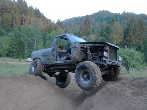 1988 Ford Bronco - This heavily modified SUV is tackling a steep dirt incline, its off-road capabilities.