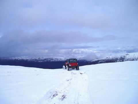 2000 Ford E350 - A red Jeep Wrangler navigates a snow-covered trail in a remote, mountainous area.