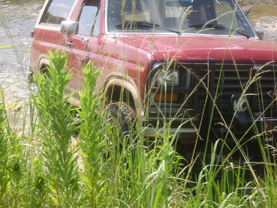 1986 Ford Bronco 3q-front view, red, driving through water