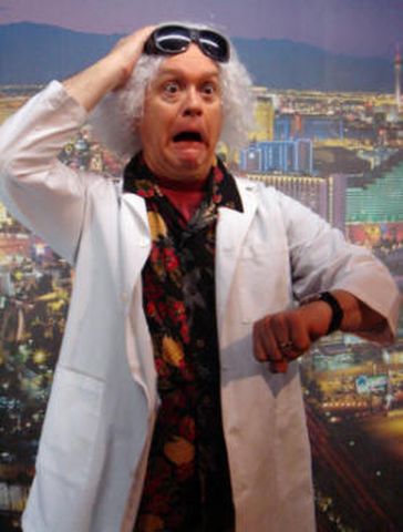 1991 Ford Crown Victoria - A man dressed as Doc Brown reacts with surprise while checking his watch against a city skyline backdrop.