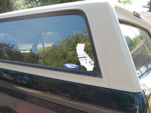 1995 Ford Bronco - Rear quarter panel view of a Ford Bronco, a California map sticker and a Ford oval sticker on the window.