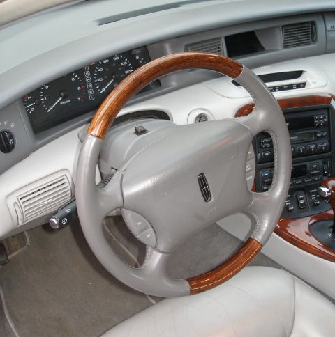 1998 Lincoln Mark VIII - The interior of a car is shown, a leather and wood steering wheel, dashboard, and center console.