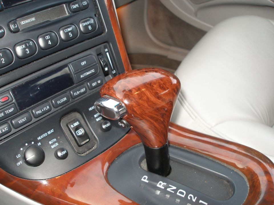 Car interior showing wood-trimmed gear shifter, climate controls, and radio