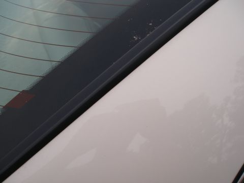 1998 Lincoln Mark VIII - Close-up view of the rear window and trunk lid of a white vehicle, showing defroster lines and a black trim piece.