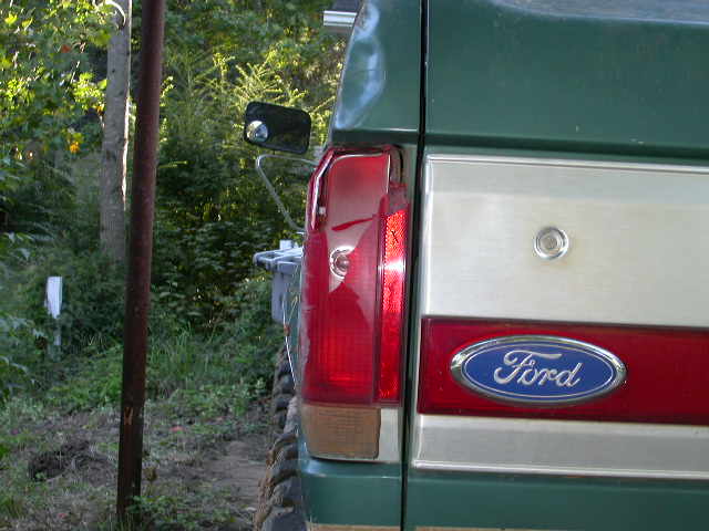 1990 Ford Bronco rear quarter panel with Ford badge and taillight. Green and tan paint scheme