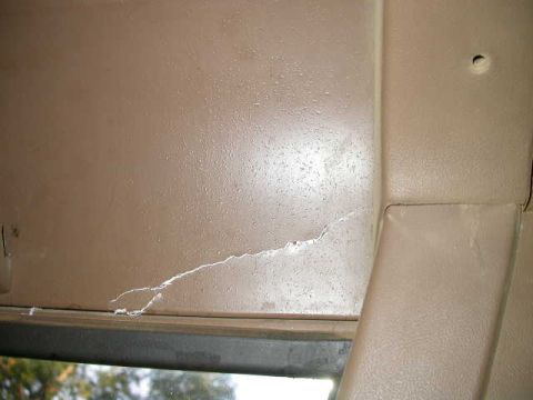 1990 Ford Bronco - Close-up of a damaged interior door panel, showing a significant crack and water staining.