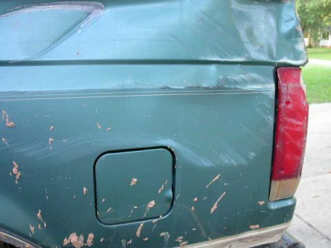 1990 Ford Bronco - The rear quarter panel of a 1990 Ford Bronco shows damage and mud splatter.