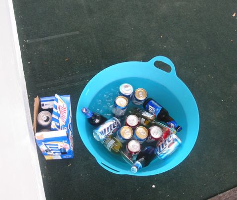 1994 Ford Taurus - A cooler full of beverages sits on a dark surface next to a partial six-pack carrier.