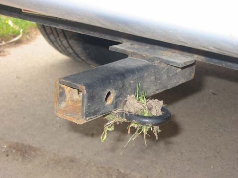 1994 Ford Taurus - A trailer hitch is visible, with grass and dirt accumulated around its safety chain loop.