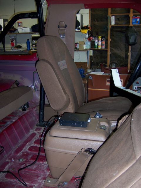 1991 Ford Bronco - The interior of a vehicle shows seats and a center console with a CB radio, with the floor stripped bare.