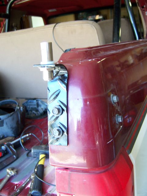 1991 Ford Bronco - A custom bracket is bolted to the exterior of a red vehicle, with tools visible in the foreground.