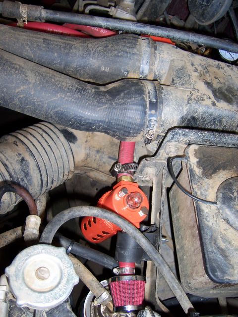 1991 Ford Bronco - Close-up of an engine bay showing an aftermarket orange air compressor with associated hoses and a small red air filter.