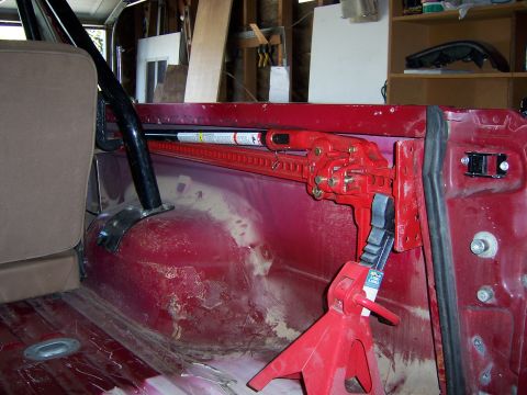1991 Ford Bronco - A high lift jack is mounted inside a red vehicle, with a jack stand providing support.