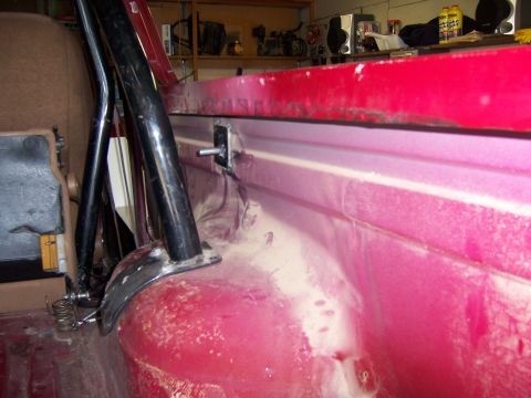 1991 Ford Bronco - Detail of a roll cage mount inside a vehicle, showing hardware and the red interior paneling.