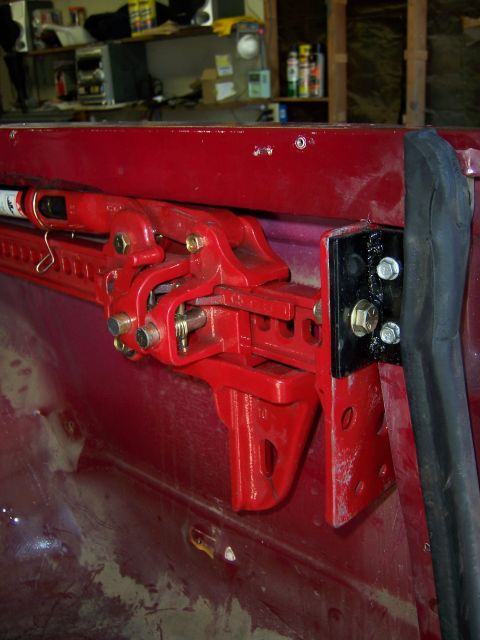 1991 Ford Bronco - A red high lift jack is mounted to the interior bed rail of a red vehicle.