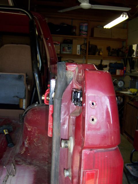 1991 Ford Bronco - Detail of a red vehicle body panel with attached hardware, possibly for a mount.