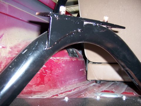 1991 Ford Bronco - Close-up view of a black spare tire carrier mount installed in the interior of a red vehicle, adjacent to tan upholstery.