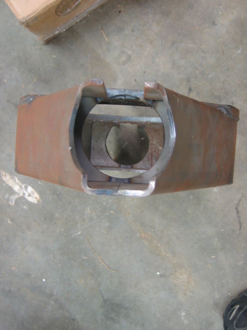 Rusty metal fabricated part with a circular opening and internal bracing