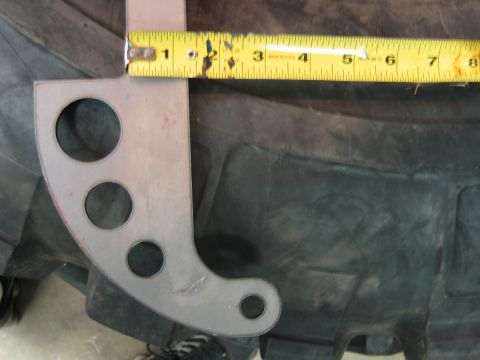 1992 Ford Mustang - A metal bracket with multiple holes is shown being measured against the tread of a large tire.