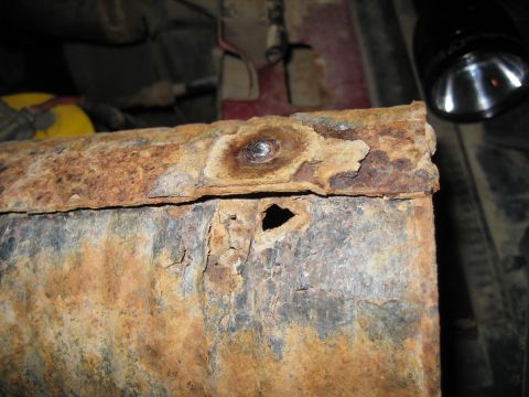 1995 Ford Bronco - Close-up of heavily corroded metal, showing significant rust and a hole.
