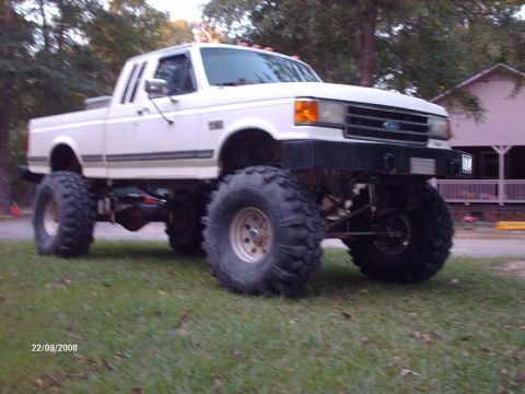 1990 Ford F-150 - White 1990 Ford F-150 pickup truck modified with a suspension lift and oversized off-road tires.