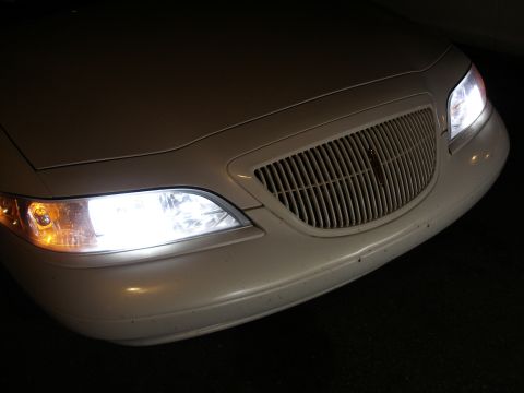 1998 Lincoln Mark VIII - The front grille and headlights of a white Lincoln Mark VIII are visible at night, with a website watermark in the corner.