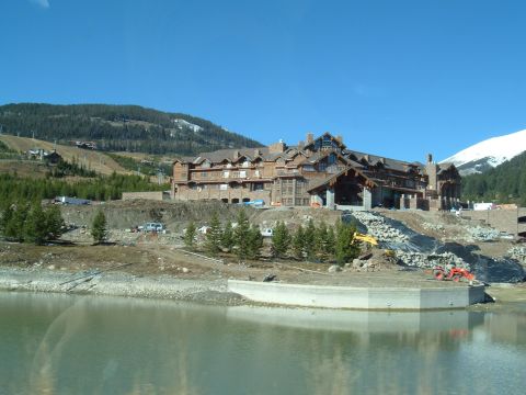 2006 Ford E350 - A large building under construction is seen next to a lake, with heavy machinery on site.