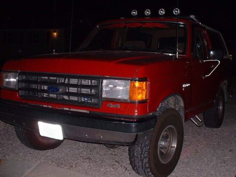 2006 Ford E350 - A red Ford Bronco is parked outside at night, showing its front and side profile.