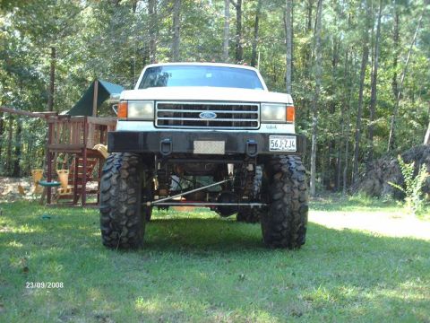 1990 Ford F-150 - This lifted Ford F-Series truck has a prominent grille and large off-road tires.