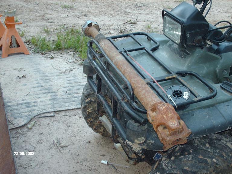 Rusty driveshaft resting on the rack of a green ATV