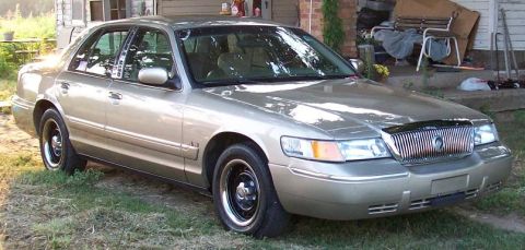 2000 Mercury Grand Marquis - Gold 2000 Mercury Grand Marquis sedan parked in front of a house.
