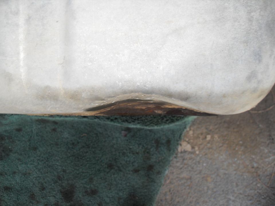 Close-up of rusted metal edge above green carpet, with Supermotors.net watermark