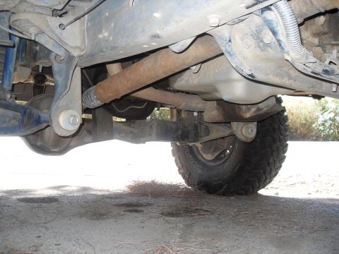 1990 Ford Bronco - A close-up view of the undercarriage reveals the drive shaft and rear axle assembly of the vehicle.