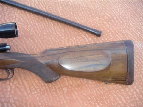 1991 Ford Bronco - Close-up view of a rifle's wooden stock and barrel, resting on a patterned surface.