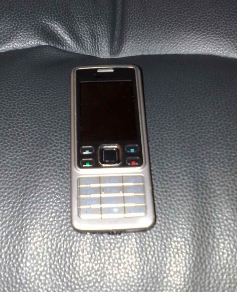 2003 Ford Crown Victoria - A silver cell phone rests on a dark, textured background.