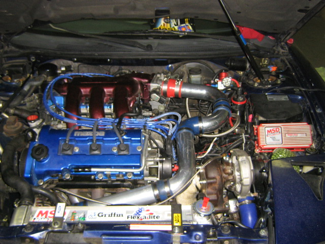 Engine bay with blue Mazda engine, turbocharger, and red MSD ignition box